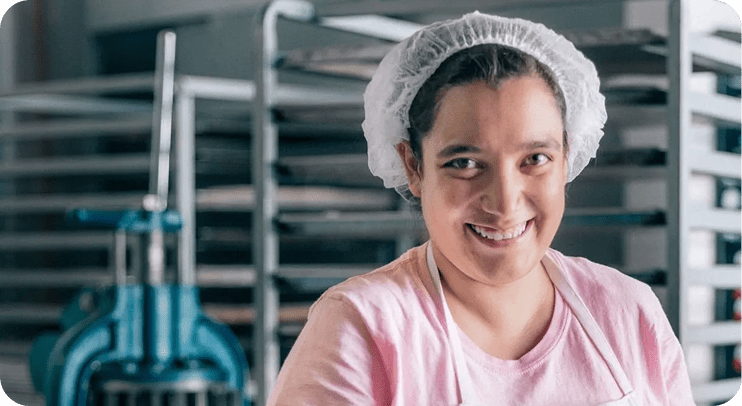 Smiling baker wearing a hairnet in kitchen.