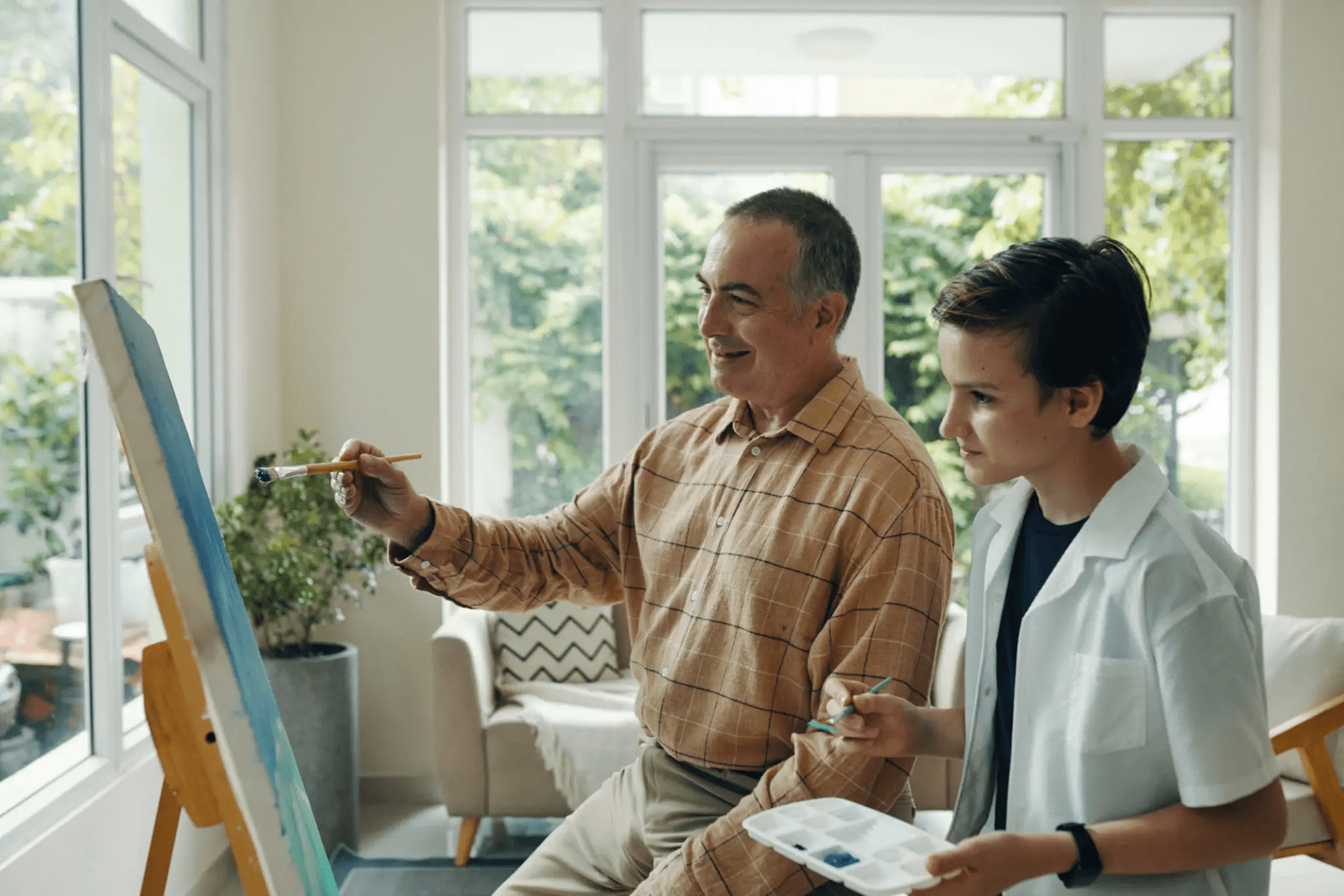 Man and boy painting on canvas together.