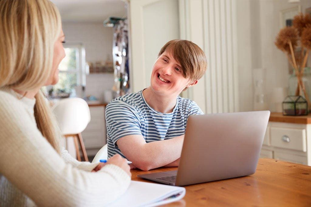 Two people smiling at a table with laptop.