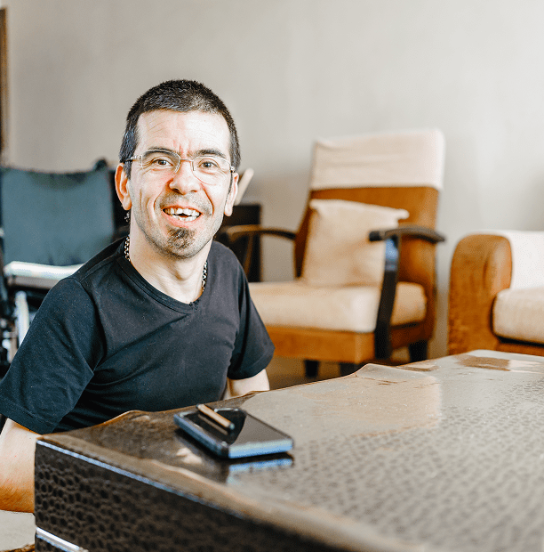 Smiling man sitting near a table.