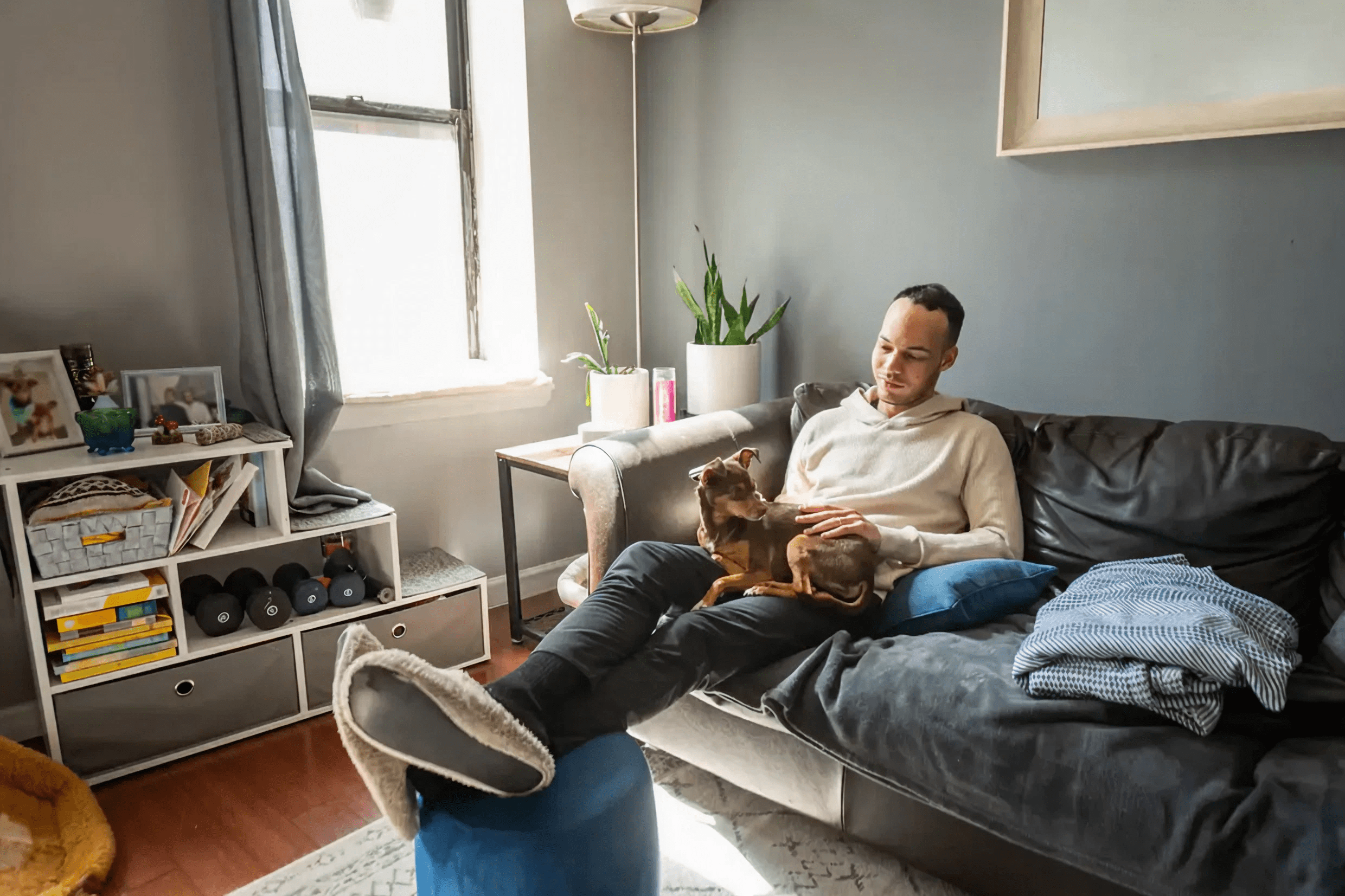 Man relaxing on sofa with small dog.